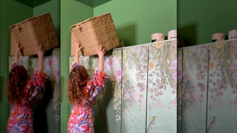 woman putting basket atop closet