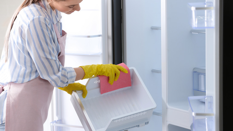 Woman scrubbing removable fridge drawer