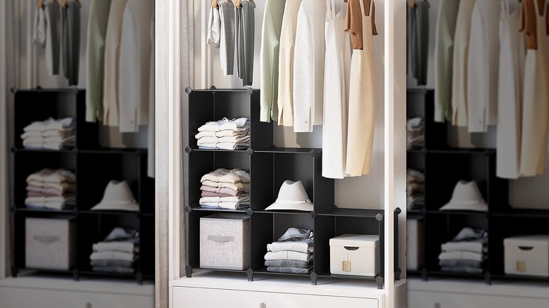 Black organizational cubes in a closet under hanging clothes