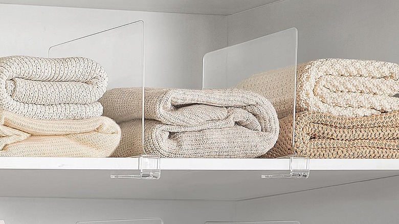 Clear shelf dividers with folded sweaters in each one