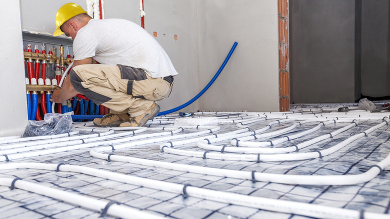 Pipe fitter installing in-floor heating