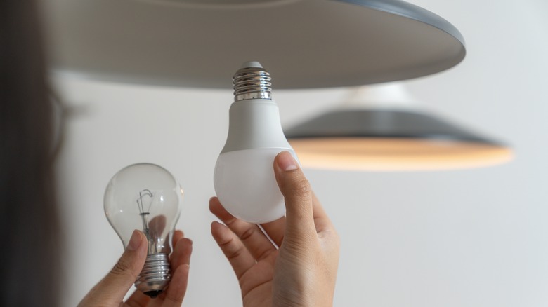 person changing light bulb in fixture