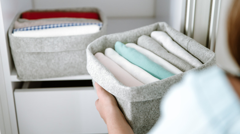 woman placing storage bin in closet