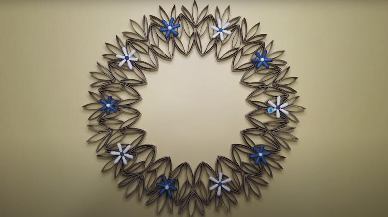 A wreath made from toilet paper rolls and adorned with flowers made from cotton swab tips.