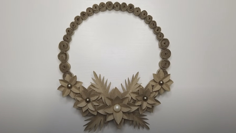 A brown wreath made from paper coils and flowers.