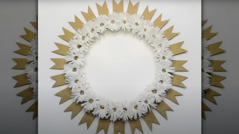 A wreath made from dozens of cardboard ribbons and white tissue paper flowers.