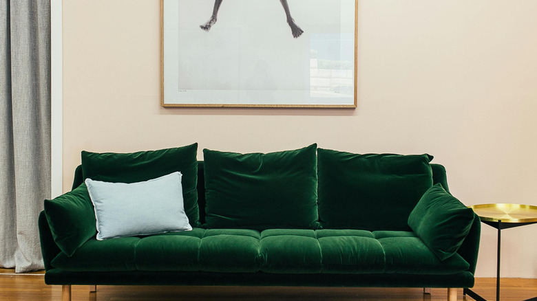 A modern living space decorated with an emerald green velvet couch.