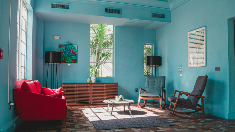 A small space painted a bold teal with ruby red accents in the furniture and art