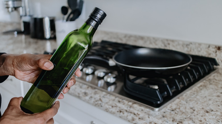 holding olive oil bottle