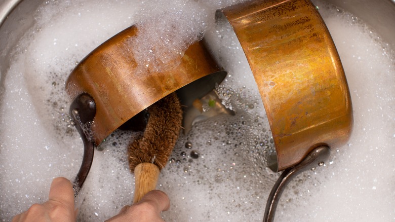 Hands cleaning a copper pot