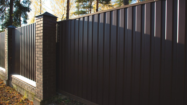 Black sliding metal fence gate with black brick pillars