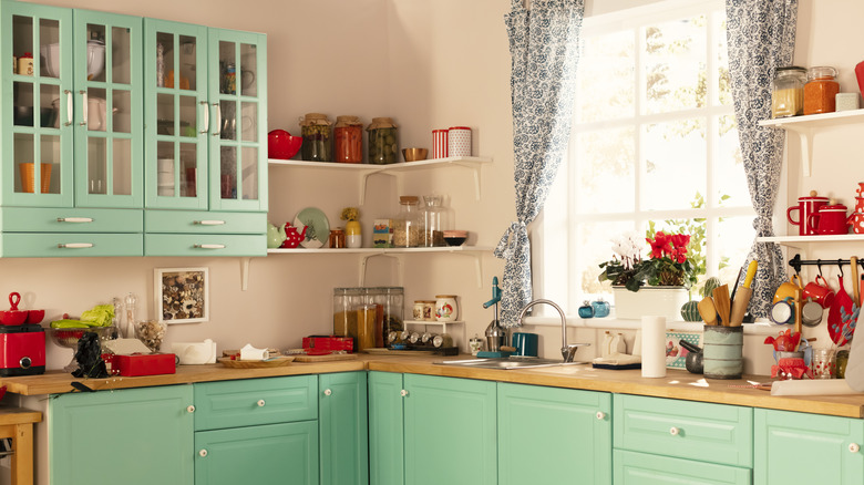 A colorful kitchen with pale pink walls and teal cabinets