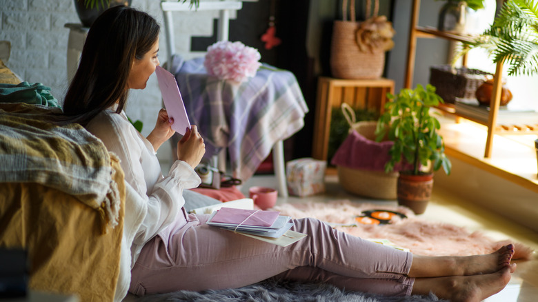 A woman smells a scented letter she is holding