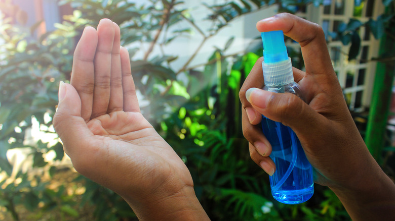 A person spraying liquid from a small spray bottle into their hands