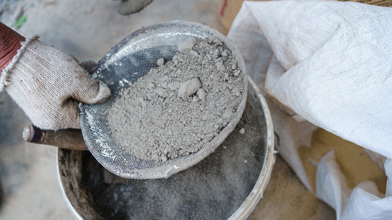 Hand sifting through gray powder