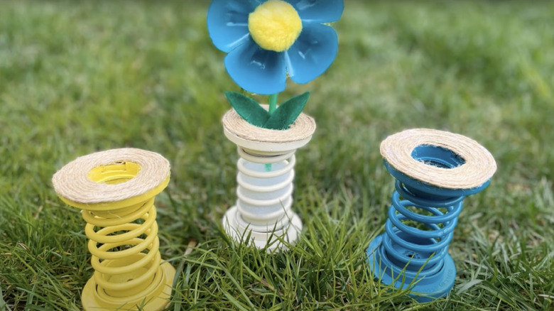 Yellow, blue, and white vases for faux flowers made from spray painted tension springs and twine.