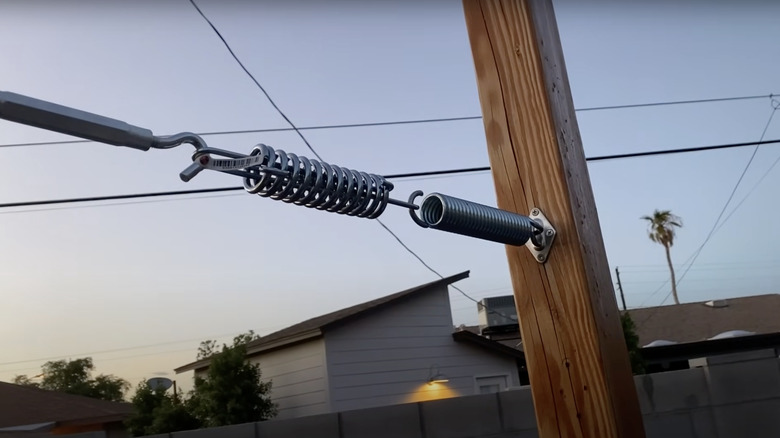 A tension spring holds a shade sail tight between the patio posts.