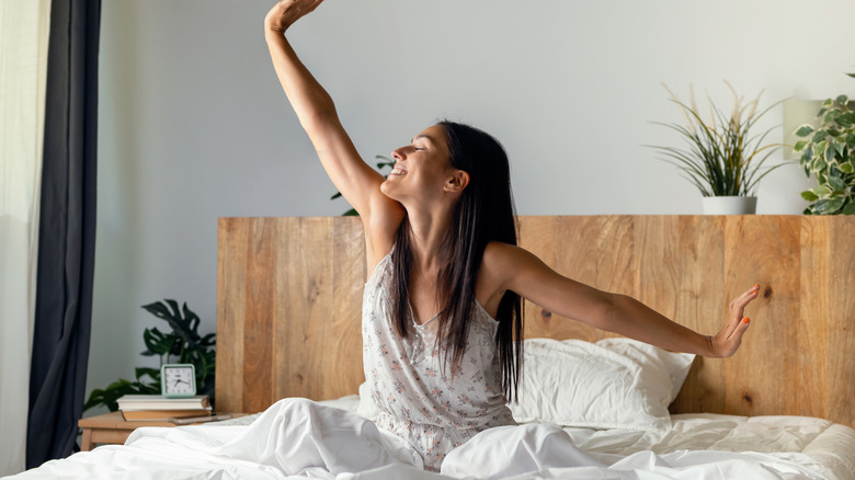 Wiman waking up and stretching her arms in bed