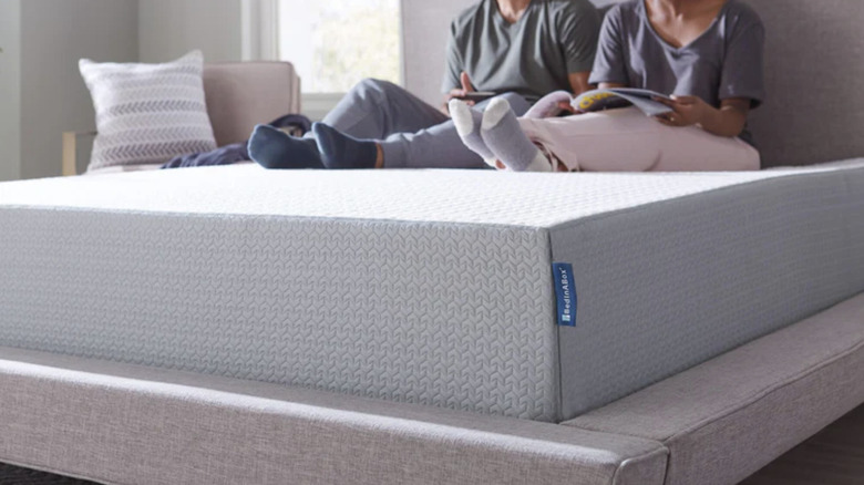 Closeup of a mattress on a platform bed with people sitting on it