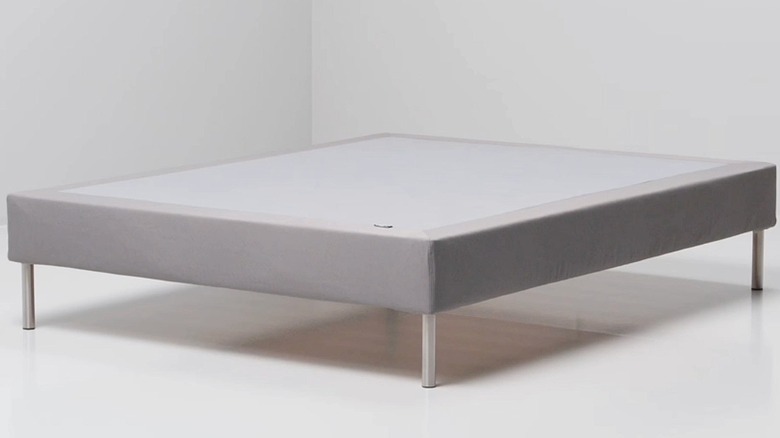 Slatted mattress base with legs covered with gray fabric