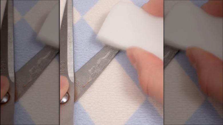 person removing glue on scissors