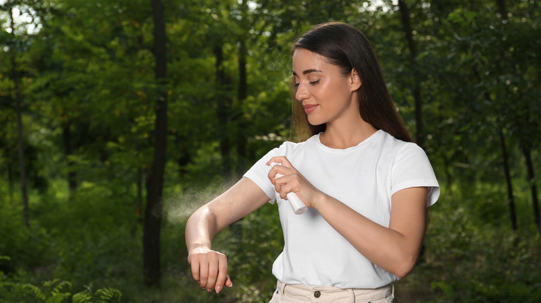 woman applying repellent outside