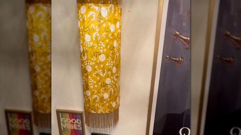 Yellow floral fabric wall sconce with fringe on wall