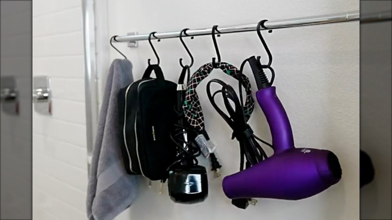 Bathroom with towels, hot tools, and personal products hanging from the shower bar using S-hooks