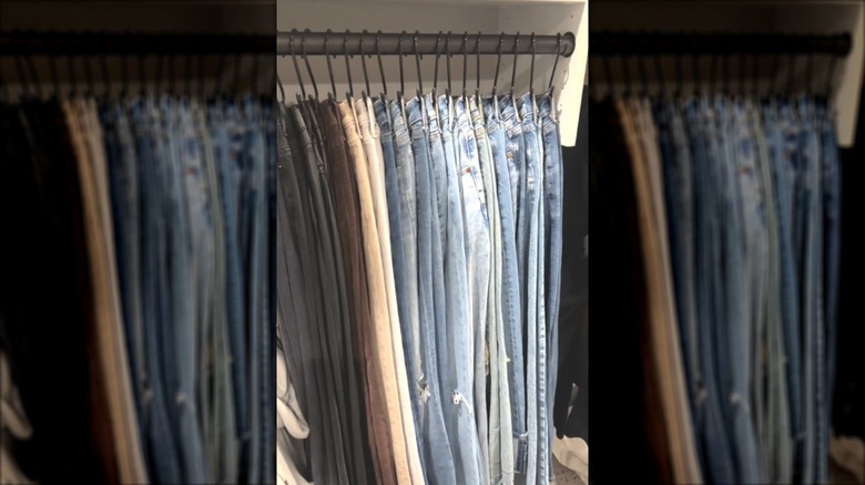 Closet with several pairs of jeans hanging from the rod using S-hooks