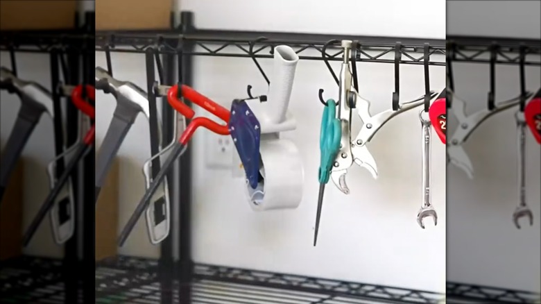 Miscellaneous tools hanging from S-hooks on a black storage rack