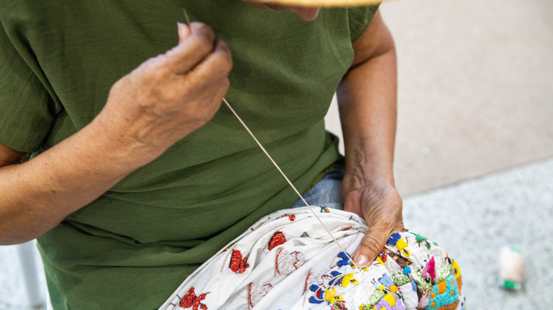 Man darning a blanket with needle and thread