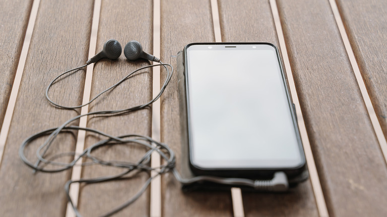 Earbuds with a wire and a cell phone on a table