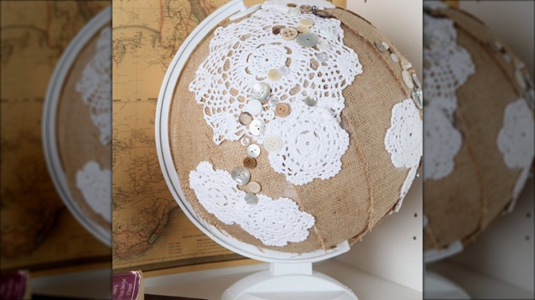 Globe covered in doilies, burlap strips, and buttons