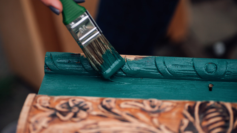 Person painting over carved wood detail