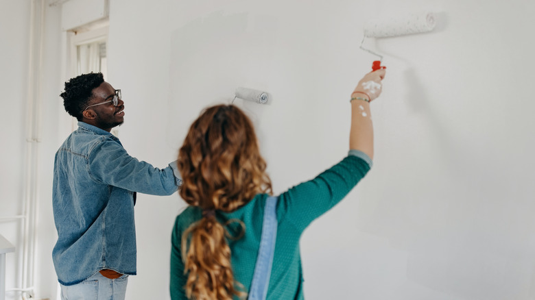 Couple having fun renovating their house and painting the walls