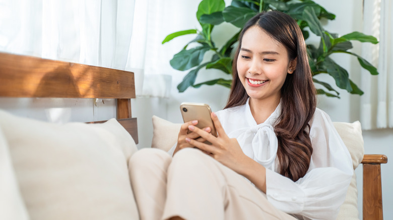 Woman looking at her phone while sitting on the sofa