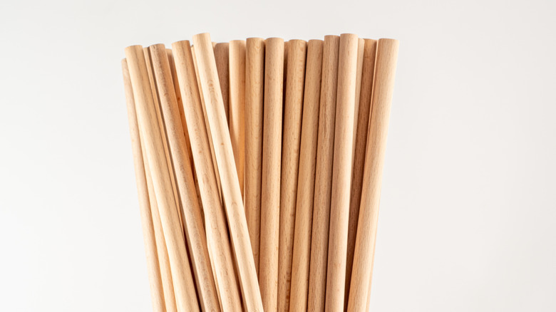 Several small wooden dowel rods are bunched together and standing up on one end.