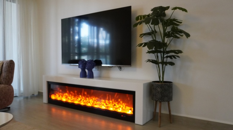 Living room with mounted television and fireplace beneath it