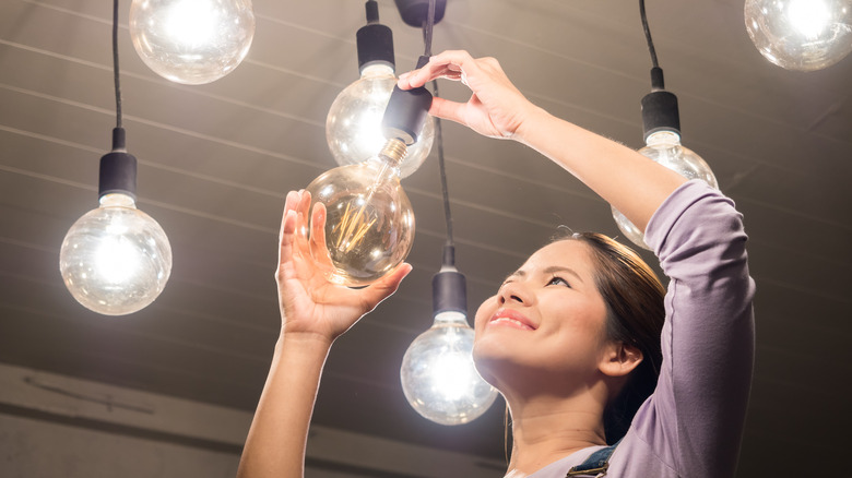 Woman mounting a pendant light in her home