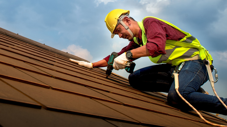 roofer nailing shingles to roof