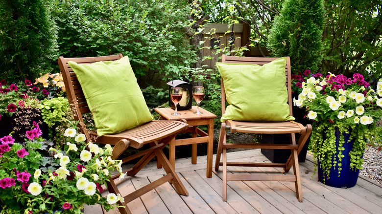 Wooden chairs on deck with flower pots.