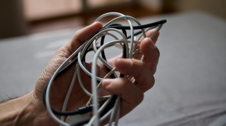 A cluttered mix of cords in a person's hand