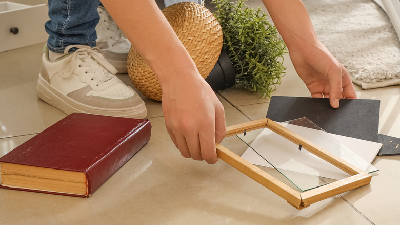 A person picking up a broken picture frame