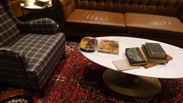 Gray gingham chair, leather sofa, and red Persian rug with coffee table