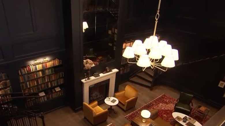 The Hotel 1928 library with dark walls, red Persian rugs, and leather furniture