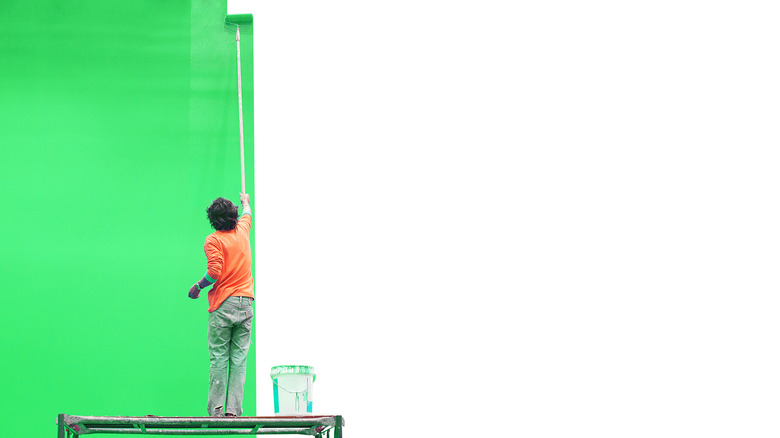 Person painting a wall green