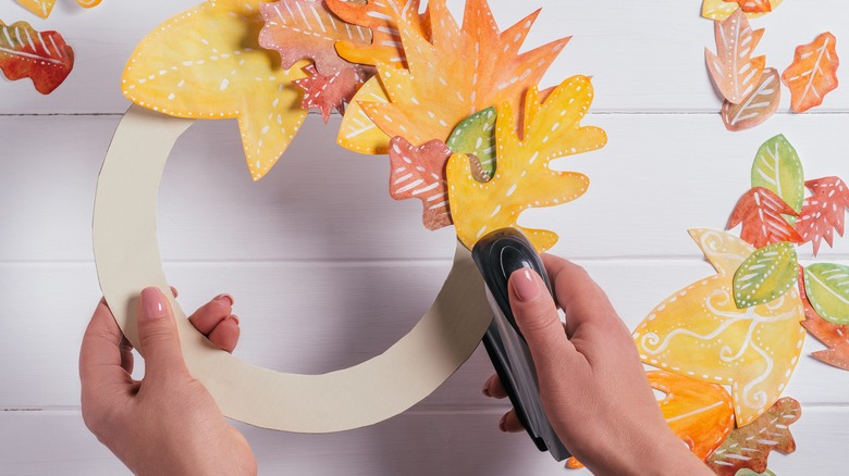 person stapling decorative fall wreath