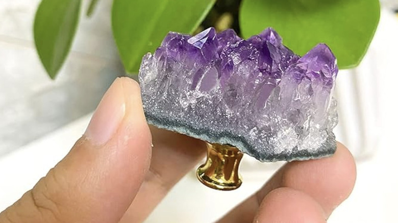 A person holding an amethyst knob for a dresser or closet door.