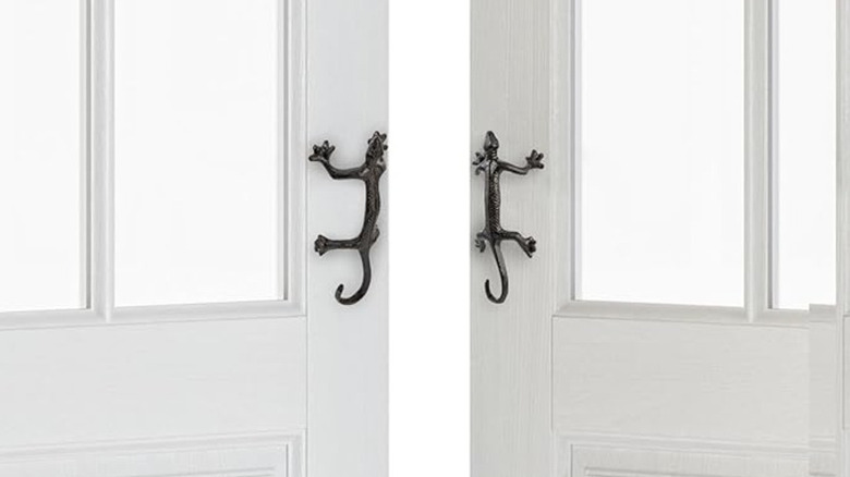 Gecko-shaped door handles on a white door.