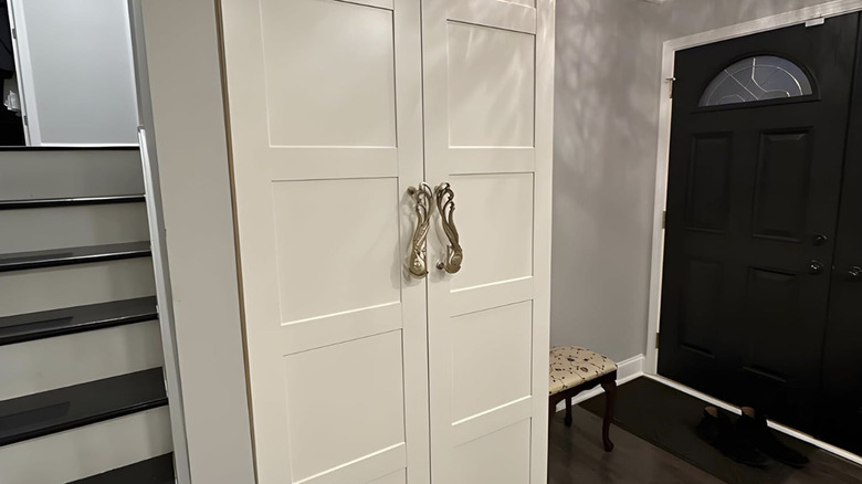 A white hallway closet with peacock handles.